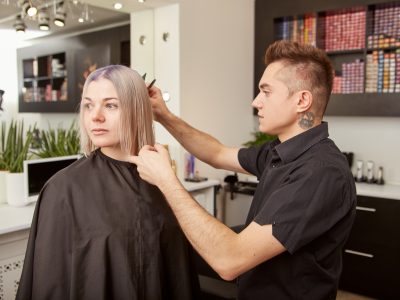 Handsome hairdresser cutting client hair in beauty salon Handsome hairdresser cutting client hair in beauty salon